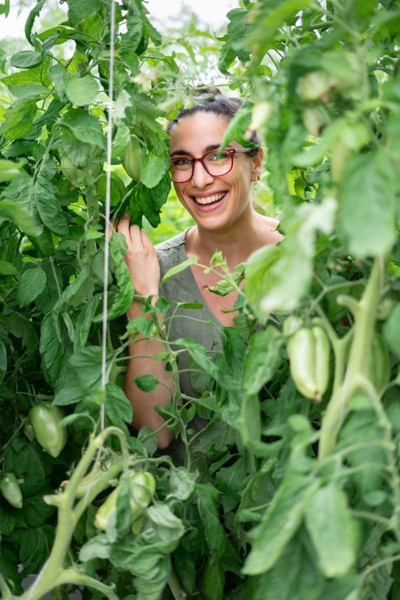 Marion Sarlé sourit derrière des plants de tomates